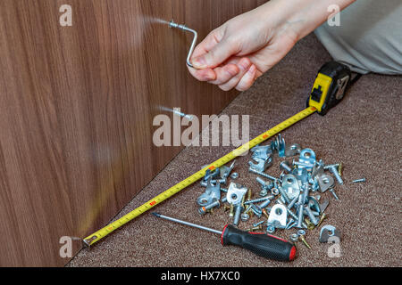 Assembling furniture using allen key, close-up hand turning hex wrench in diy furniture. Stock Photo