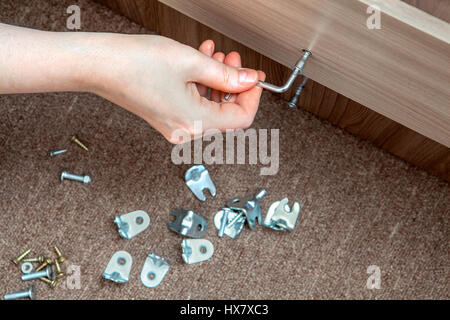 Self-assembly furniture, hand with an Allen key tighten screw. Stock Photo