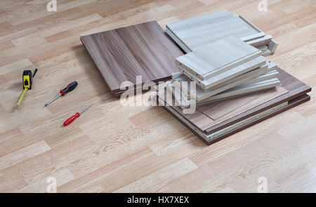 Flat pack furniture lying on floor at home next to hand tools for assembly. Stock Photo