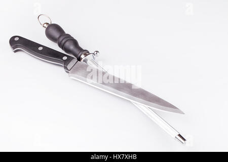 Knife and knife sharpener musat on a white surface. Knife and knife sharpening steel isolated on white background. Stock Photo