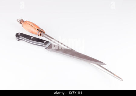 Knife and knife sharpener musat on a white surface. Knife and knife sharpening steel isolated on white background. Stock Photo