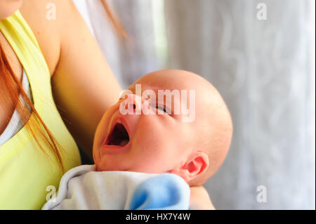 One month old baby yawning while holding her mothers hand. Stock Photo