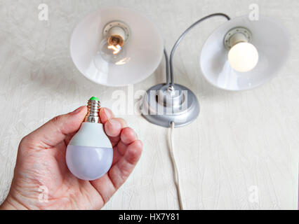 Upgrading your home's lighting by replacing old, inefficient incandescent light bulbs with new, energy-efficient LED lamp, Electric LED light bulb hel Stock Photo