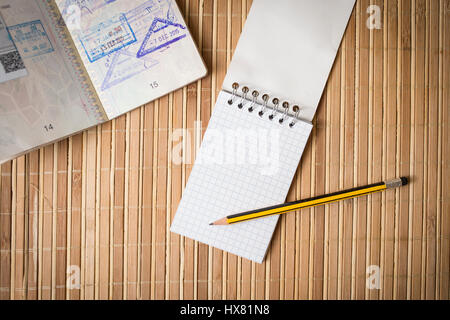 Passport, notepad and pencil on a bamboo table Stock Photo