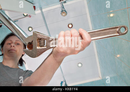 Woman unscrews the old, wrong faucet aerator to sink in the bathroom, using an adjustable wrench plumber. Stock Photo