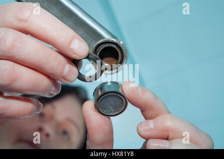 Woman plumber installing faucet aerator,  close-up of hand handyman repairing a tap in the bathroom. Stock Photo