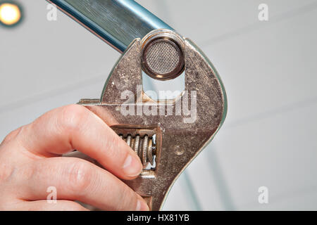 Replace a Sink Aerator using an adjustable plumbing spanner , hands plumber close-up. Stock Photo
