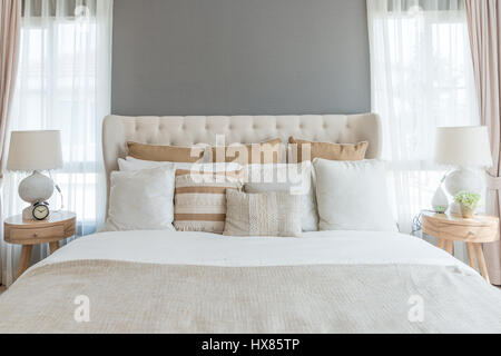 Bedroom in soft light colors. big comfortable double bed in elegant classic bedroom at home. Stock Photo