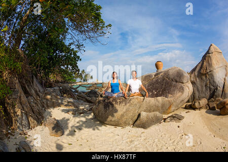 Young couple doing yoga exercises on the beach Stock Photo