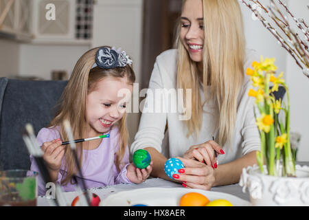 Easter, family, holiday and child concept - close up of little girl and mother coloring eggs for Easter Stock Photo