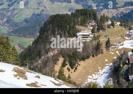 Red funicular and yellow cable car arriving at their respective top stations in Stoos, a mountain village in central Switzerland. Stock Photo