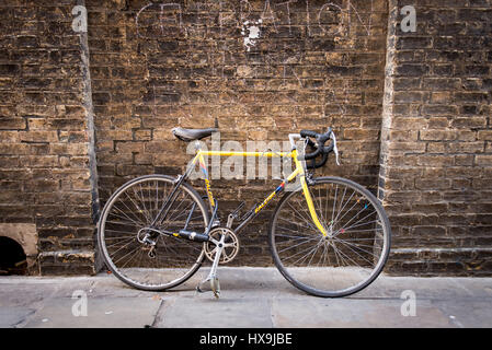 Old locked racing bike or bicycle leaning against an old wall Stock Photo