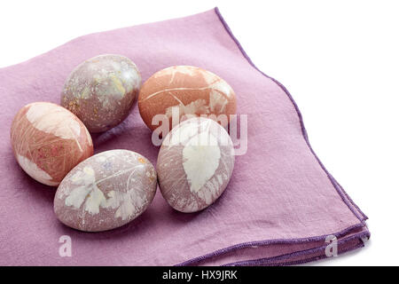 Five painted easter eggs on violet textile napkin over white Stock Photo