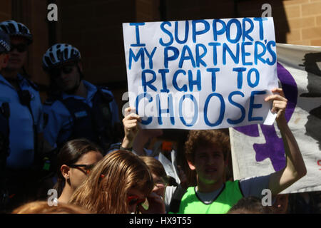 Sydney, Australia. 26 March 2017. After Mass at St. Mary's Cathedral Sydney, the Very Reverend Archbishop Anthony Fisher led the Rosary Procession with police escort through the Domain to the back of Parliament House on Hospital Road where they stopped for 20 minutes for a short address and prayers. A counter-protest of abortion supporters rallied outside St Mary's Cathedral before marching to the front of Parliament House on Macquarie Street. Pictured: A pro-abortion counter protester holds a sign saying, ‘I Support My Partners Right To Choose' outside St Mary's Cathedral. Credit: Richard Mil Stock Photo