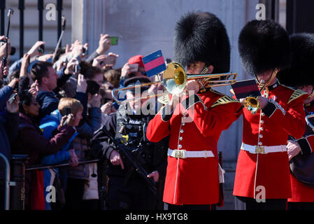 London, UK.  26 March 2017.  Armed police are present in front of crowds of tourists as Foot Guards take part in The Changing the Guard ceremony at Buckingham Palace.  With the arrival of British Summer Time today, the Foot Guards change from their grey winter great coats to their iconic red and gold tunics. Credit: Stephen Chung / Alamy Live News Stock Photo