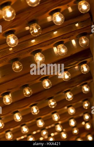 Plenty light bulbs shining bright. Many lightbulbs in rows on ceiling burn. Stock Photo
