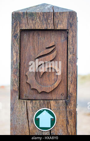 Welsh Coast Path sign with symbol on made of wood with a directional arrow pointing to direction on Talacre Beach, Flintshire, North Wales Stock Photo