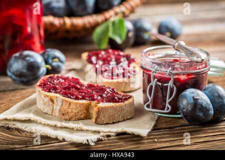 Sandwich with plum jam on old wooden table Stock Photo