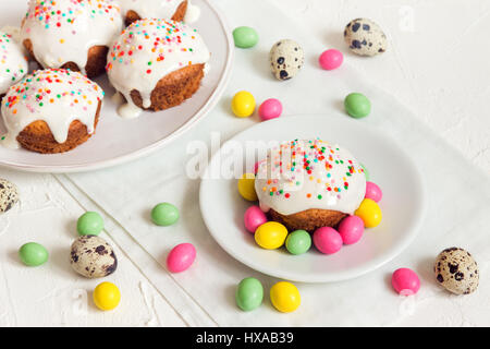 Easter cakes with white icing and easter festive decor on white background with copy space - homemade festive pastry and easter eggs Stock Photo