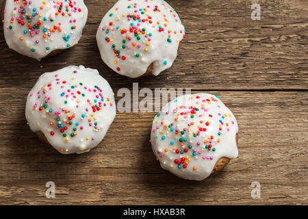 Easter pastry. Fresh Homemade Carrot Mini Cakes with White Creamy Sugar Icing and Colorful Decor over wooden background with copy space. Easter Cakes  Stock Photo