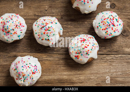 Easter pastry. Fresh Homemade Carrot Mini Cakes with White Creamy Sugar Icing and Colorful Decor over wooden background with copy space. Easter Cakes  Stock Photo