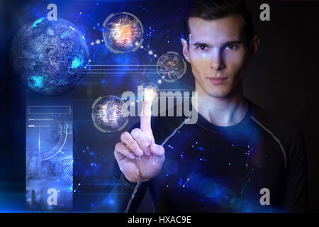 Man touching digital planets on hologram screen with his finger Stock Photo