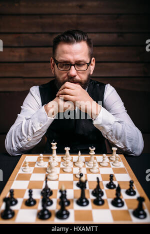 Pensive male chess player in glasses thinking about game strategy. Intelligence competition concept Stock Photo