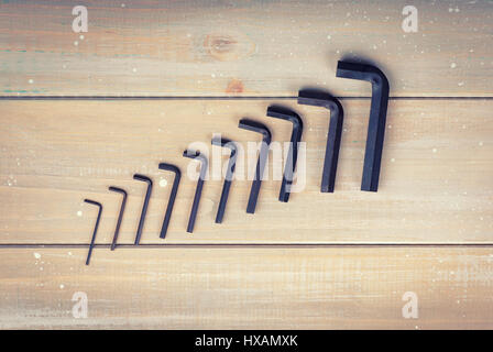 Old hex keys are laid out from the smaller to the larger on a wooden background Stock Photo