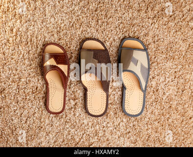Three different sized slippers stand on a fleecy carpet. View from above Stock Photo