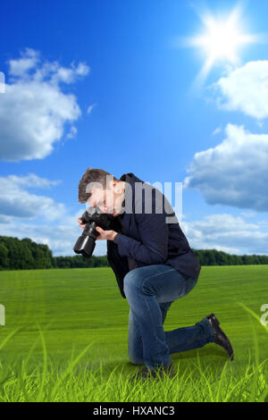 Photographer taking macro picture of the grass on digital camera, green meadow on background Stock Photo