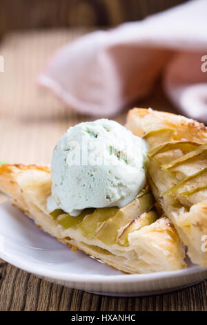 Sliced homemade apple tart on rustic wooden board and served with ice cream on white plate Stock Photo