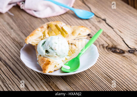 Sliced homemade apple tart on rustic wooden board and served with ice cream on white plate Stock Photo