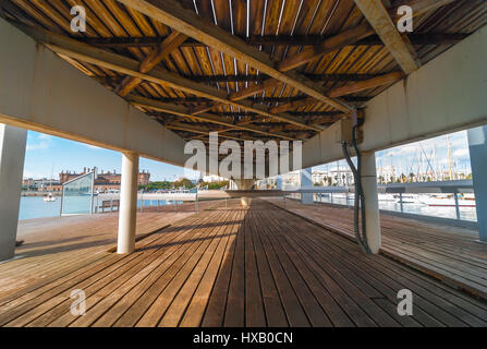 View of the marina Port Vell from under the pedestrian walkway concourse that connects the entertainment & shopping centre to the city waterfront. Stock Photo