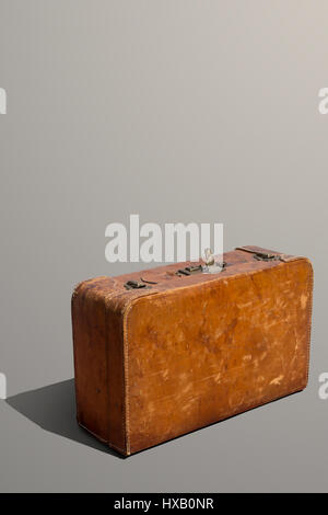 Dusty and scratched old leather standing suitcase Stock Photo