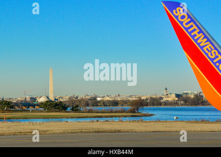 The tip of a Southwest airlines wing is seen in foreground on the taxiway of Reagan National Airport with the Washington Monument in distance, DC. Stock Photo