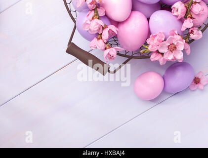 Easter eggs and   blooming peach branch on   wooden table.