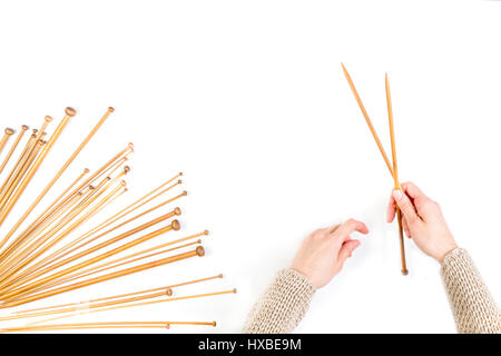 Woman hands holding a pair of wooden knitting needles. Many different size bamboo knitting needles on white background Stock Photo