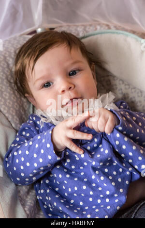 Happy three month old baby girl in her swing playing with her shirt Stock Photo