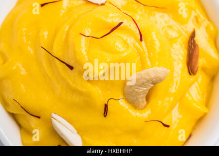 hapus or alphonso Mango pudding / Mango shrikhand or srikhand or amrakhand - Mango dessert with condensed milk magoes and nuts, selective focus over w Stock Photo