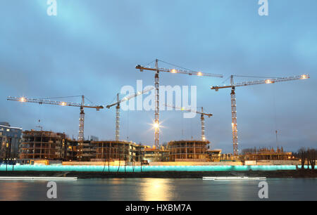 Construction site of a residential building, tower cranes with evening lights mast and jib. Stock Photo