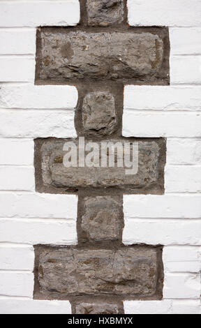 Closeup of a white painted brick wall with large gray stones forming interesting pattern. Stock Photo