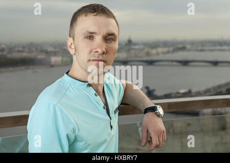 A young man 27 years old, Caucasian, Slav, Russian, dressed in a turquoise shirt with short sleeves, horizontal portrait, close-up, against the backgr Stock Photo