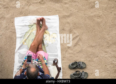 Elderly man using mobile phone on beach Stock Photo