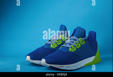 New pair of colorful running shoes isolated on blue background. Sport footwear for exercise in gym Stock Photo