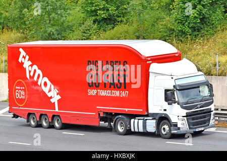 Red TK Maxx mobile advertising side of long streamlined shop delivery trailer & white large hgv Volvo lorry truck driving on Essex English UK motorway Stock Photo