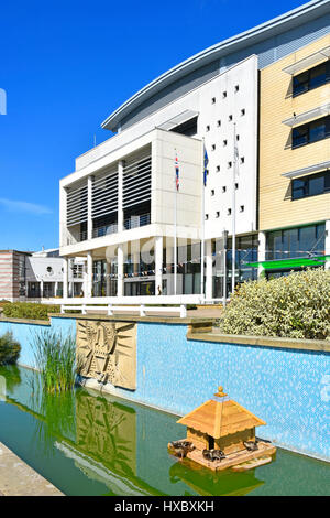 Duck House in landscaped water feature & garden for ducks in front of Harlow new town Civic Centre & town hall building entrance Essex England UK Stock Photo