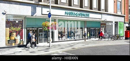 Marks and Spencer M&S shop front windows in high street retail shopping centre shoppers walking along pedestrian paved over road Slough Berkshire UK Stock Photo