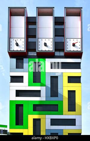 Gimmicky modern clock hands on clock tower top of colorful modern architecture student accommodation flats colourful geometric rectangle pattern UK Stock Photo