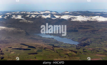 A aerial view of Ullswater in the Lake District, Cumbria, with snow capped mountains in the background, as the warm weather continues for many in the UK. Stock Photo