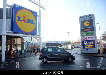 A shopper in a car leaves the car park at the Plough Lane Retail Park in south west London SW19 in front of the Lidl supermarket Stock Photo